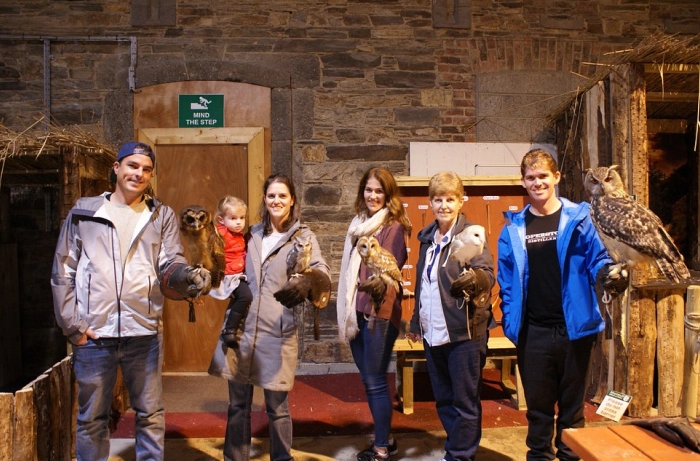 Adults and child holding several owls.