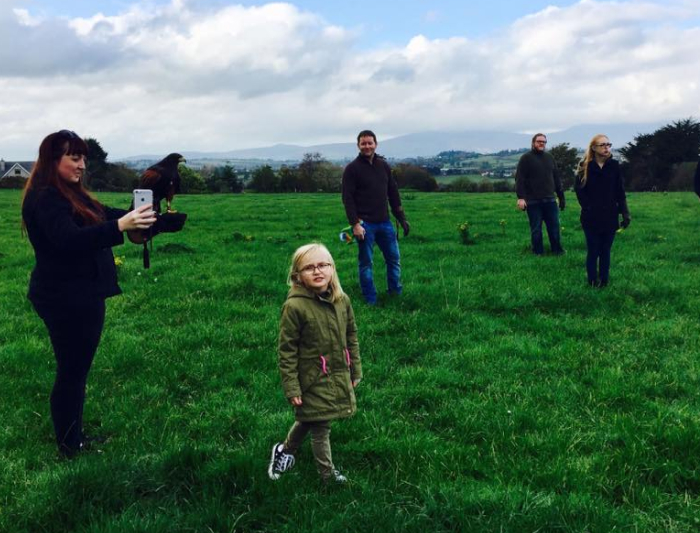 Family standing in green field with hawk.
