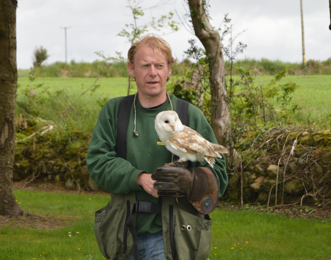 Man holding barn owl outdoors.