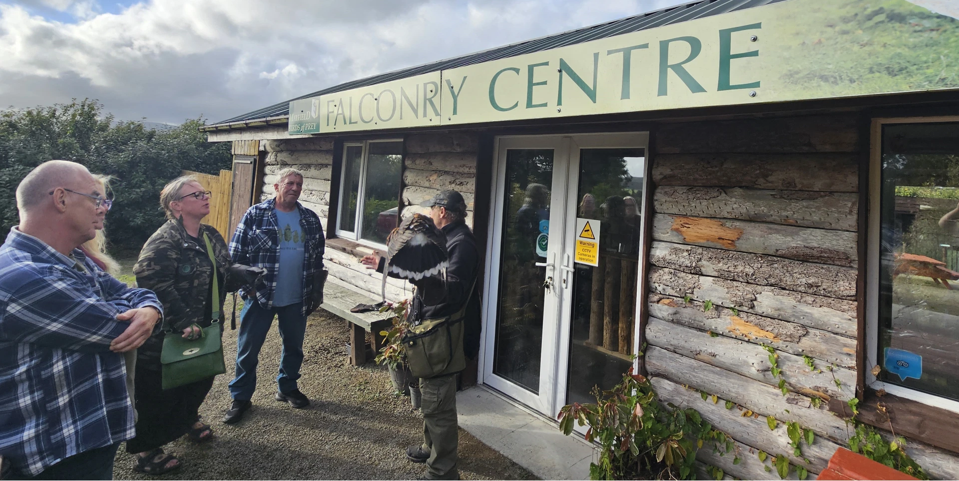Group standing outside rustic falconry centre.