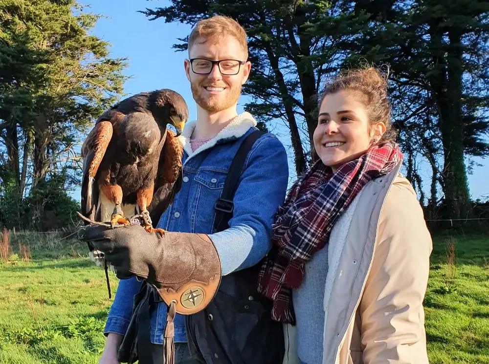A young couple holding a hawk, smiling.